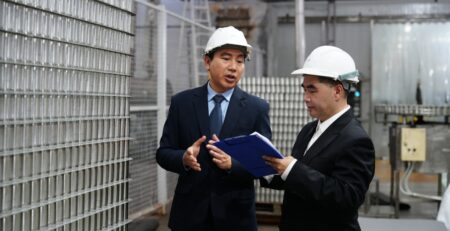 Manufacturing CEO redefining growth to his partner in a suit on the factory floor