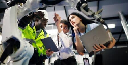 Technical sales man showing/inspecting robotic arm to man and woman