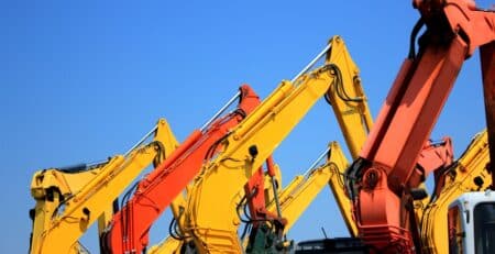 Arms of construction and heavy equipment against blue sky background