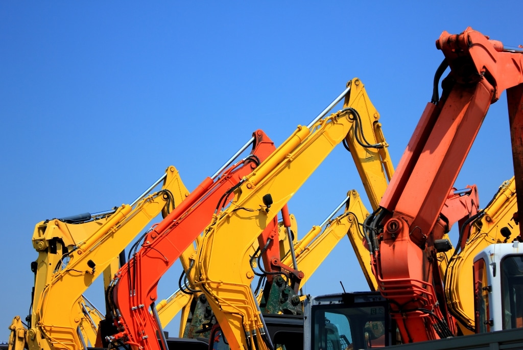 Arms of construction and heavy equipment against blue sky background