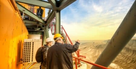 2 men discussing executive hiring while overlooking a quarry from heavy equipment balcony