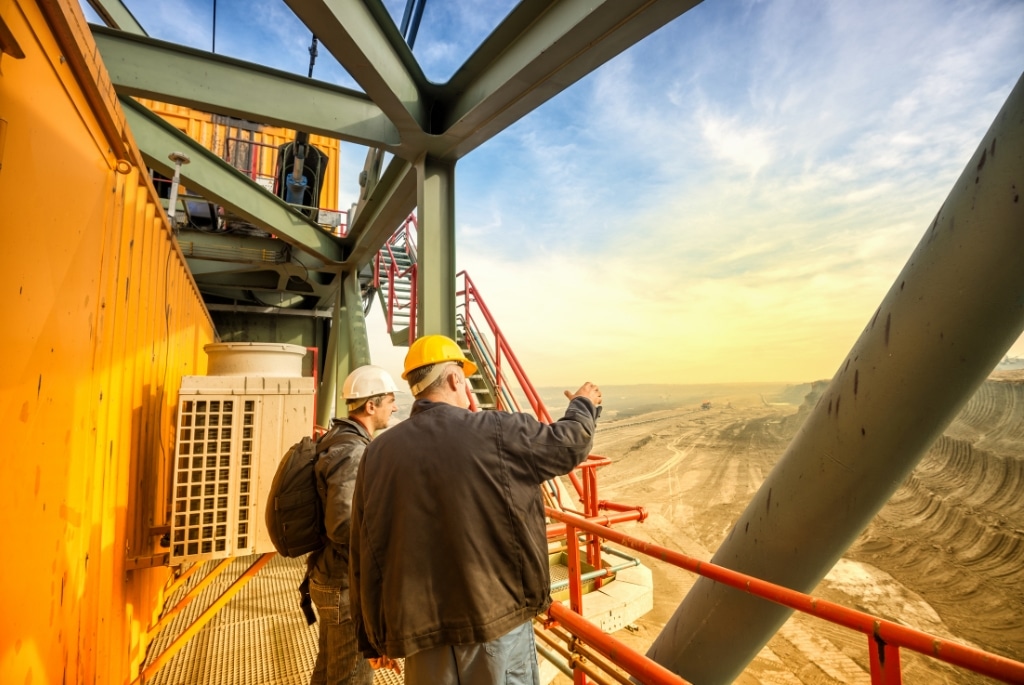 2 men discussing executive hiring while overlooking a quarry from heavy equipment balcony