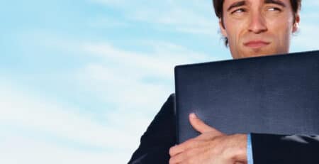 Man with cringing face hugging briefcase